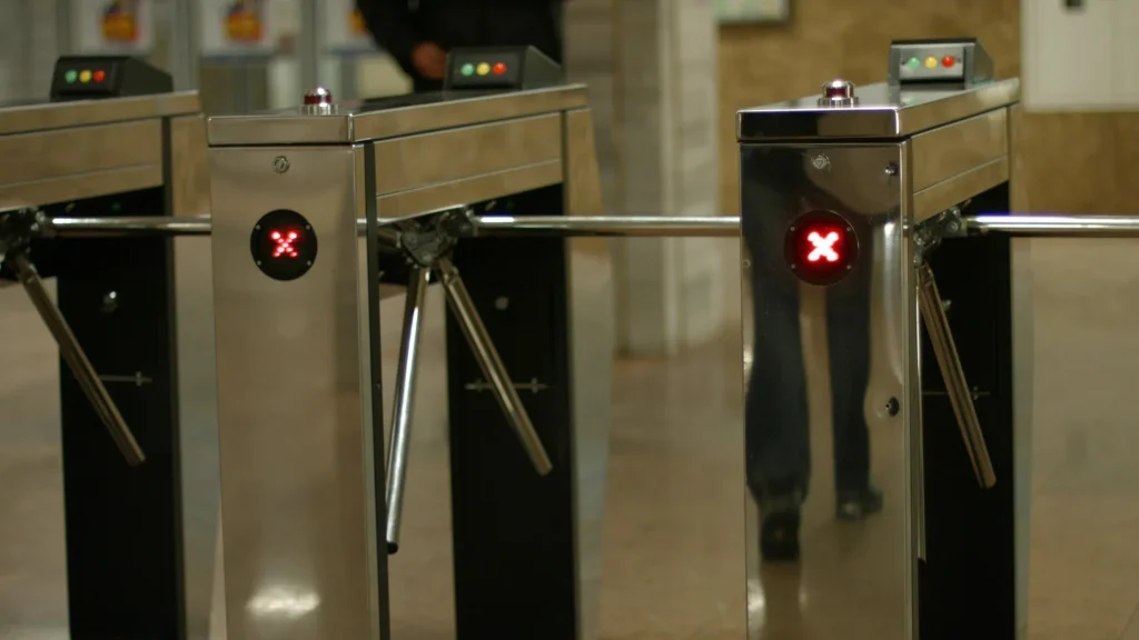 Diferencia visual de un molinete de metro con aspas metálicas frente a un torniquete de oficina o portillo libre.